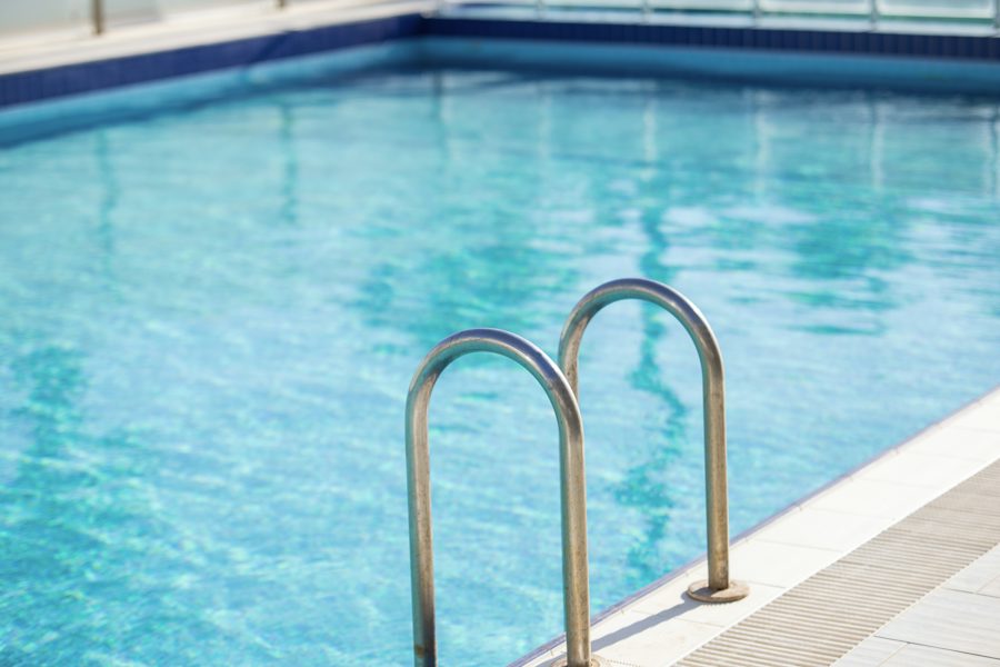 Escaleras de acero inoxidable en una piscina de agua clara